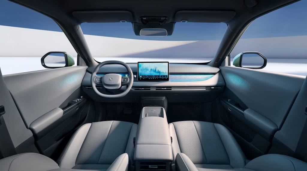 Interior de um carro moderno, com bancos cinza-claros e painel escuro. Um volante minimalista e uma tela central exibem uma paisagem de montanhas nevadas. Detalhes em azul-claro iluminam o painel e as portas, criando uma atmosfera futurista. O exterior visível pelas janelas é um cenário branco e azul, sugerindo um ambiente de estúdio ou neve