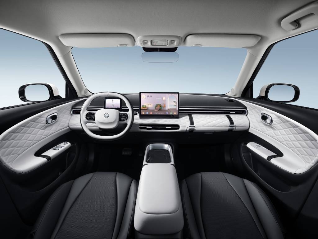 Interior de carro moderno com painel preto e branco, volante branco, tela multimídia central e bancos pretos. Detalhes acolchoados brancos nas portas e no painel, console central branco.