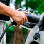 carregadores de carros elétricos mão de pessoa plugando um carregador em carro elétrico ou híbrido plug in branco. autonomia carro elétrico
